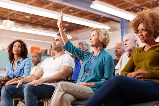 Senior in a classroom setting raises her hand.