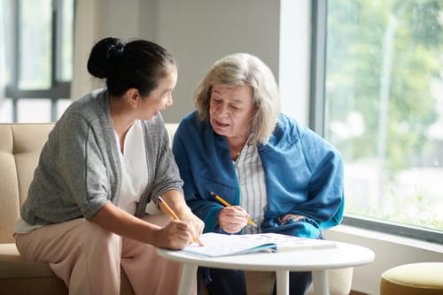 A caregiver helps a senior woman with paperwork.